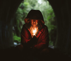 Man in dark cave lit by candle he is holding